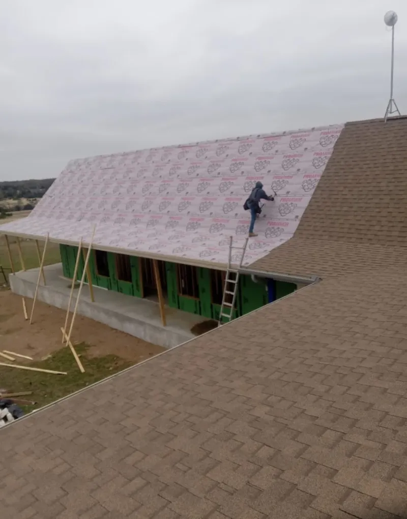 Worker preparing underlayment for a metal roof installation in Draper
